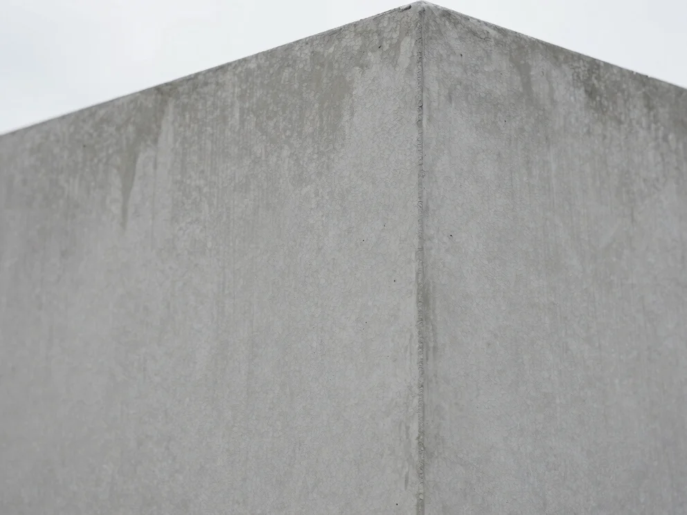 Tight detail crop of a freshly plastered architectural surface, showing smooth texture and sharp edges under bright neut